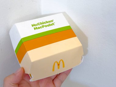 Calgary, Alberta, Kanada. 14. kat, 2025. Bir el McDonald 's McChicken burger kutusunu tutuyor, bej, turuncu ve yeşil katmanlı tasarımı sergiliyor, markanın simgesel sarı logosu 