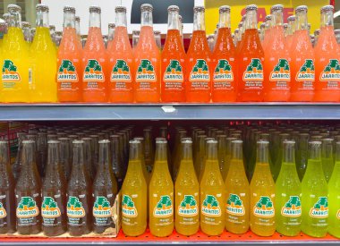 Calgary, Alberta, Kanada. Mar 13, 2025. Cam şişelerdeki renkli Jarritos gazozları raflarda düzgünce yerleştirilmiş, çeşitli meyve aromaları sergileniyor..