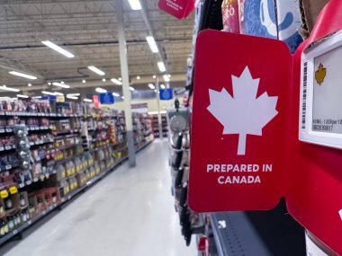 Calgary, Alberta, Kanada. 26 Aralık 2025. Ön planda beyaz akçaağaç yaprağı ve CANADA 'da PrePARED yazısının yer aldığı kırmızı etiketli bir market koridoru. Mağaza rafları dolu..