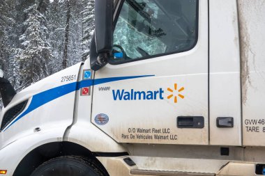 Banff, Alberta, Kanada. 4 Nisan 2025. Beyaz bir Walmart yarı kamyon taksisi. Muhtemelen Calgary, Alberta, Kanada 'da park edilmiş. Arka planda karla kaplı ağaçlar görünür..