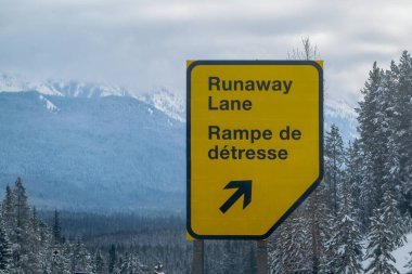 Calgary, Alberta, Kanada. 4 Nisan 2025. Sarı ve siyah yol işareti, dağlık bir bölgede yukarı doğru ok atan bir Kaçak şeridi gösteriyor..