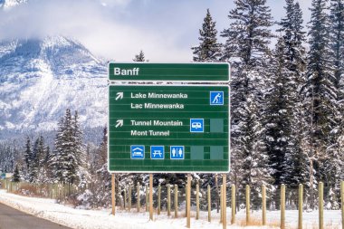 Banff, Alberta, Kanada. 4 Nisan 2025. Banff yakınlarındaki büyük yeşil beyaz tabela Minnewanka Gölü ve Tünel Dağı 'na giden yolu gösteriyor..