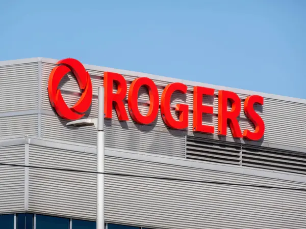 Calgary, Alberta, Kanada. 5 Nisan 2025. Pürüzsüz kırmızı Rogers logosu, açık mavi gökyüzüne karşı ticari bir binanın dış kısmında belirgin bir şekilde belirginleşmişti..