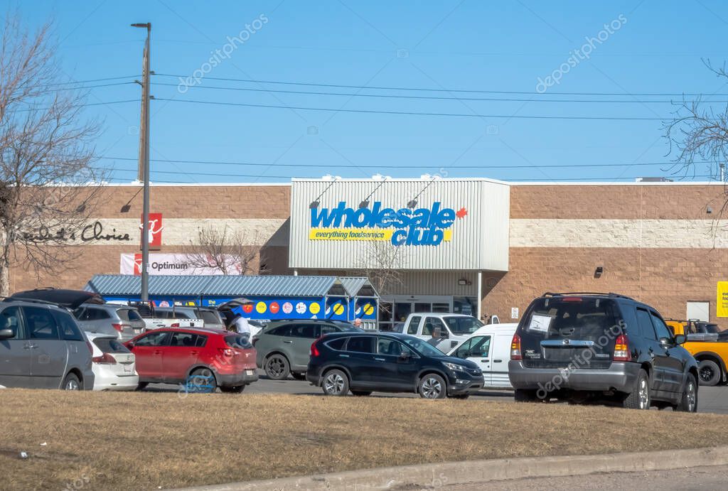 Calgary, Alberta, Canada. Apr 5, 2025. Exterior view of a Wholesale Club store, featuring its logo on the facade above a busy parking lot on a clear day.