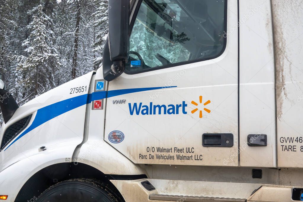 Banff, Alberta, Canada. Apr 4, 2025. A white Walmart semi-truck cab parked, likely in Calgary, Alberta, Canada, given the previous context. Snow-covered trees are visible in the background.