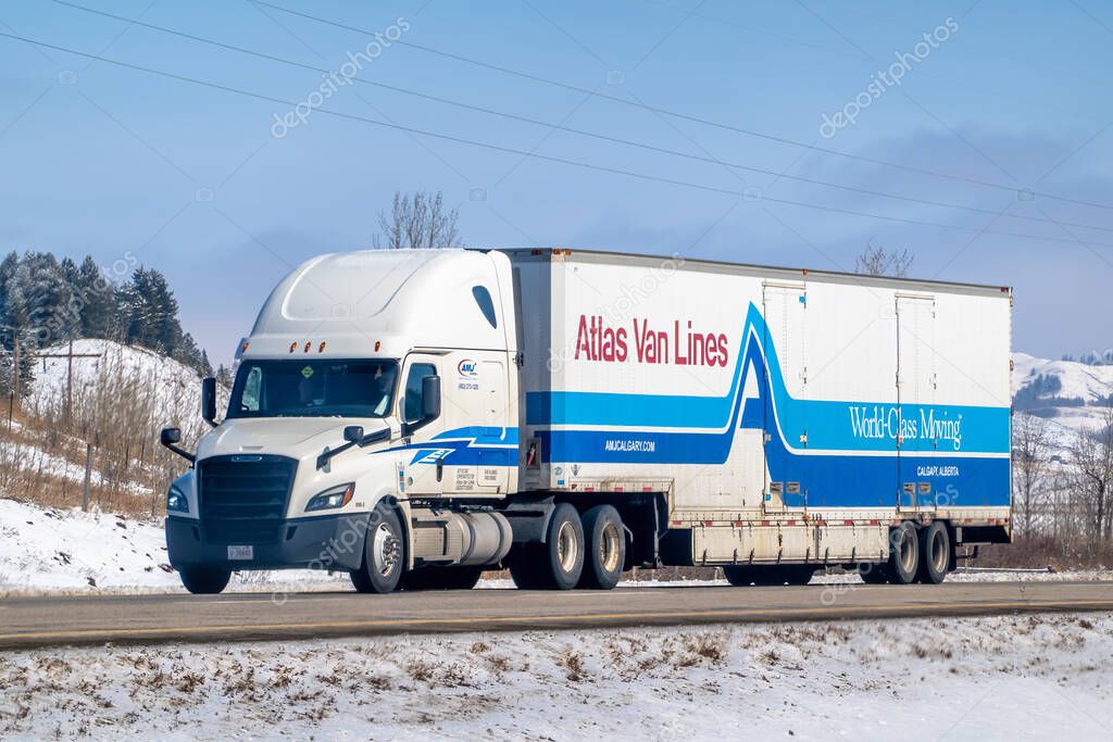 Calgary, Alberta, Canada. Apr 4, 2025. A white Atlas Van Lines semi-truck with blue and red accents, operated by AMJ Calgary, traveling on a snowy road in Calgary, Alberta.