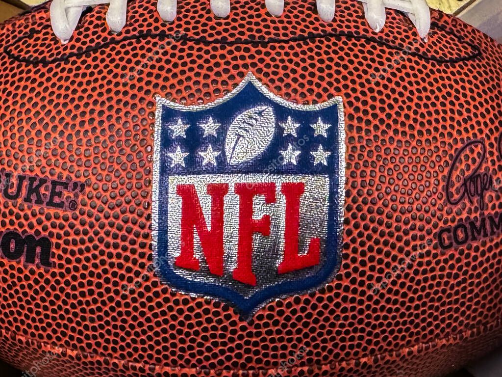 Calgary, Alberta, Canada. Apr 8, 2025. A detailed close-up shows the textured surface of an NFL football with the shield logo prominently displayed.