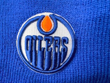 Calgary, Alberta, Kanada. 10 Nisan 2025. Yakından bakınca, mavi örgü kumaş üzerine işlenmiş Edmonton Oilers logosu görülüyor. Logoda beyaz ve mavi dairesel tasarım içinde mavi harflerle 