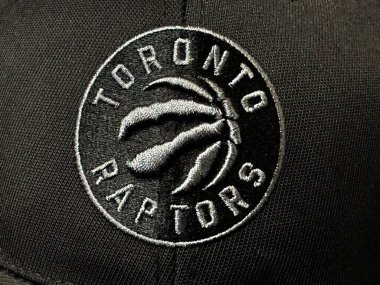 Calgary, Alberta, Kanada. 10 Nisan 2025. Toronto Raptors logosunun yakın çekimi, takım adına sahip dairesel çerçevenin içinde pençe izleri olan bir basketbol topu. Siyah ve beyaz