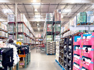 Calgary, Alberta, Kanada. 10 Nisan 2025. Bir Costco toptancı dükkanının içi, parlak ışıkların altında alışveriş arabaları ve toptan mallarla dolu uzun koridorlarla dolu..