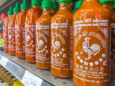 Calgary, Alberta, Kanada. 10 Nisan 2025. Bir rafta, beyaz horoz logosu ve yeşil şapkalarından tanınan birden fazla Huy Fong Sriracha acı biber sosu şişesi sergileniyor..