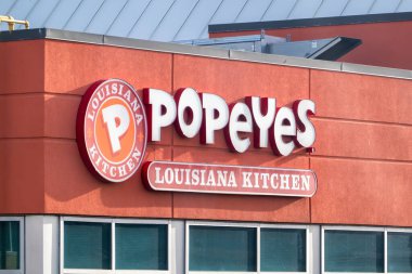 Calgary, Alberta, Kanada. 13 Nisan 2025. Portakal kırmızısı cepheli, belirgin logoları ve büyük yansıtıcı pencereleri olan bir Popeyes Louisiana Mutfak Restoranı..
