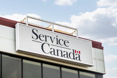Calgary, Alberta, Kanada. 13 Nisan 2025. Kanada Servisi 'nin dış işaretidir. Yumuşak bulutlu parlak bir gökyüzünün altında Kanada bayrağı sergilenmektedir..