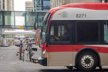 Calgary, Alberta, Kanada. 13 Nisan 2025. Bir Calgary Transit otobüsü, bisiklet parkında diğer araçlar ve yaya üstgeçitleriyle birlikte iki bisiklet tutarken görülüyor..