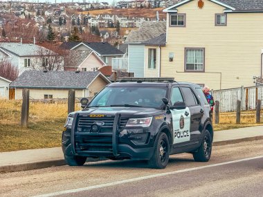 Calgary, Alberta, Kanada. 13 Nisan 2025. Bir Calgary polis cipi banliyö caddesi boyunca park halinde. Evler ve tepelerle çevrili..