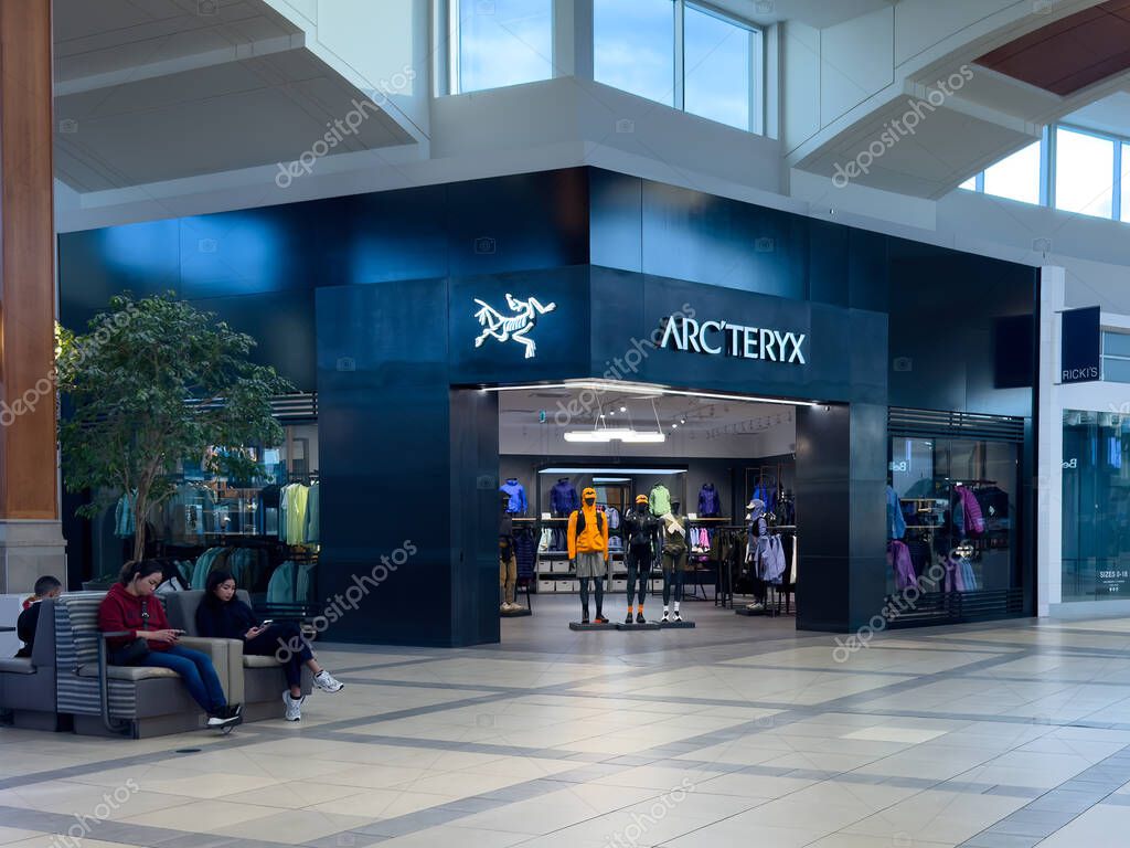 Calgary, Alberta, Canada. Apr 16, 2025. A modern ARC'TERYX store with a dark facade and brightly lit white logo and name above the entrance displays outdoor apparel.