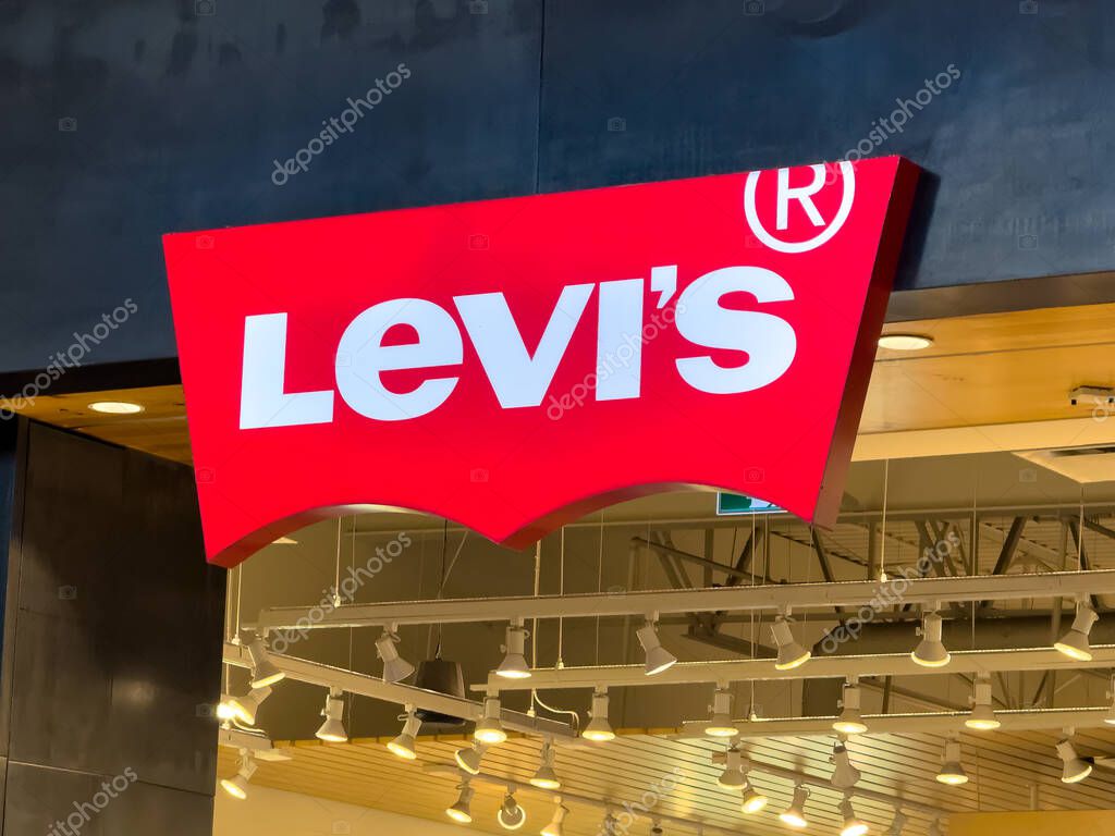 Calgary, Alberta, Canada. Apr 16, 2025. A brightly lit red Levi's logo sign prominently displayed against a dark background, in a store or retail location.