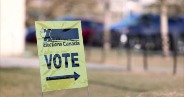 Calgary, Alberta, Kanada. 18 Nisan 2025. Koyu siyah metin ve okun yanında parlak sarı bir akçaağaç yaprağı ve bir akçaağaç yaprağı bulunan bir Kanada Seçim tabelası nerede oy kullanılacağını gösteriyor..
