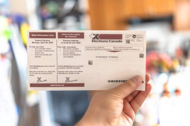 Calgary, Alberta, Kanada. 18 Nisan 2025. Bir seçmen, federal seçimlerin tarihini ve oy kullanma kurallarını gösteren resmi bir Kanada Seçim kartı tutuyor..