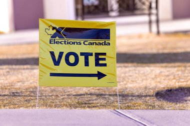 Calgary, Alberta, Kanada. 18 Nisan 2025. Sarı arka planda akçaağaç yaprağı ve koyu siyah metin ile işaretlenmiş bir Kanada Seçimleri işareti, Kanada 'nın oy kullanma yerini belirler..