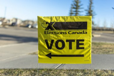 Calgary, Alberta, Kanada. 18 Nisan 2025. Kanada Seçimleri 'nden canlı sarı bir işaret, akçaağaç yaprağı ve koyu siyah yazılar gösteriyor,.