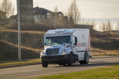 Calgary, Alberta, Kanada. 18 Nisan 2025. Bir GardaWorld zırhlı kamyonu Calgary, Alberta 'da arka planda konut binaları olan bir yolda ilerliyor..