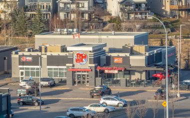 Calgary, Alberta, Kanada. 18 Nisan 2025. Güneşli bir günde Calgary, Alberta 'da verandalı ve otoparklı bir Boston Pizza restoranı gösterilir..