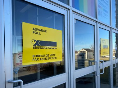Calgary, Alberta, Kanada. 18 Nisan 2025. Bir akçaağaç yaprağı ve güçlü siyah harfler sergilenirken, sarı Seçim Kanada tabelası bir oy kullanma istasyonunun girişini işaret ediyor.