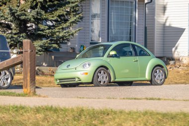 Calgary, Alberta, Kanada. 14 Nisan 2025. Açık yeşil bir Volkswagen Beetle, açık renkli bir evin önüne park etmiş..