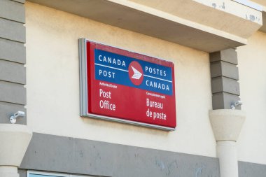 Calgary, Alberta, Kanada. 14 Nisan 2025. Bir binanın dış tarafında, posta hizmetleri için yetkili bir dağıtıcı konumunu gösteren bir Kanada Posta tabelası gösterilir..
