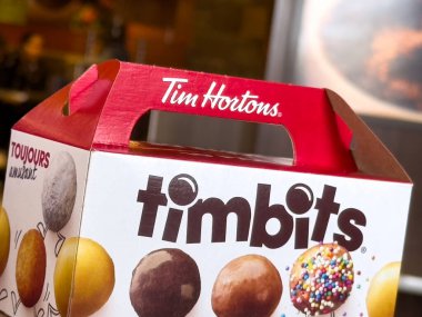 Calgary, Alberta, Kanada. 24 Nisan 2025. Kırmızı ve beyaz Tim Hortons Timbit kutusunun yakın çekim görüntüsü, farklı malzemelerle çeşitli donut deliklerini gösteriyor. Kutuda 
