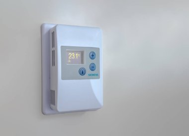 Calgary, Alberta, Kanada. 24 Nisan 2025. Beyaz bir Siemens oda sıcaklığı sensörü, açık bej bir duvara monte edilmiş. Ekranda 23.1C ve artı eksi düğmeleri var..