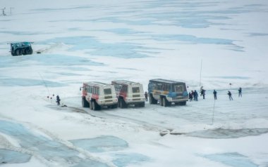 Jasper, Alberta, Kanada. 4 Mayıs 2025. Birkaç buz kaşifi, Kolombiya Buz Sahası 'nda karlı ve buzlu bir araziye park etmiş. İnsanlar otobüslerin yanında görünür ve manzara beyaz kar karışımı..