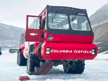 Jasper, Alberta, Kanada. 4 Mayıs 2025. Karlı buza park etmiş kırmızı ve siyah bir Columbia Icefield tur otobüsü. Otobüsün önünde 