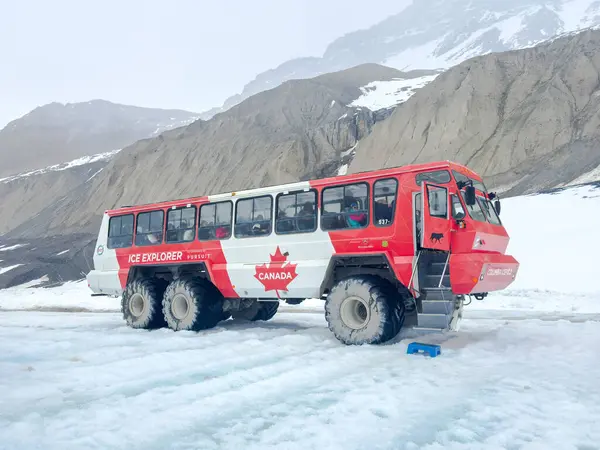 Jasper, Alberta, Kanada. 5 Mayıs 2025. Buzul seyahati için tasarlanmış kırmızı ve beyaz bir buz kaşifi otobüsü Kolombiya Buz Sahası 'nın karlı arazisinde bir dağ zeminine karşı duruyor..