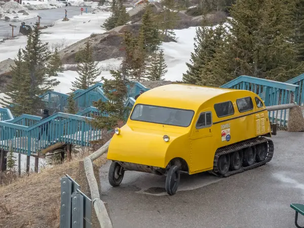 Jasper, Alberta, Kanada. 4 Mayıs 2025. Sarı kar motosikleti gibi bir araç mavi merdivenlerin yakınına park etmiş, Columbia Icefield Yorumlama Merkezi 'nde..