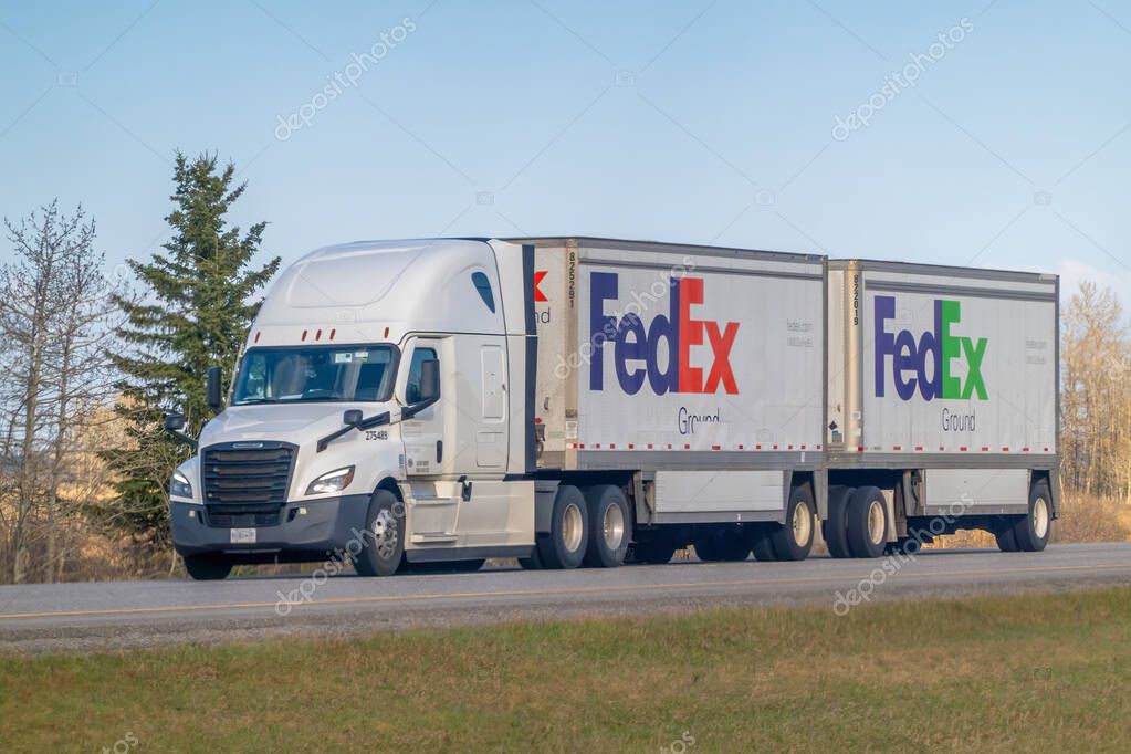 Rocky View County, Alberta, Canada. May 5, 2025. A FedEx Ground double trailer truck travels along a highway under a clear sky, symbolizing logistics and the movement of goods across the landscape.