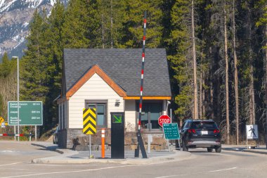 Jasper, Alberta, Kanada. 9 Mayıs 2025. Ormanın ortasında bir sınır kapısı var, bir araç yaklaşıyor. İşaretler Saskatchewan Geçidi, Jasper ve Rocky Dağı arasındaki mesafeyi gösteriyor.