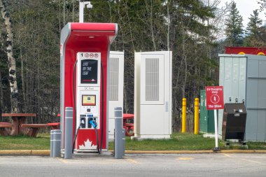 Calgary, Alberta, Kanada. 9 Mayıs 2025. Kırmızı ve gri bir Petro-Canada EV şarj istasyonu, bir Kanada bayrağı ve 'LeAF ile Yaşam' tabelasıyla işaretlenmiş, elektrikli araçlar için hazır bekliyor..