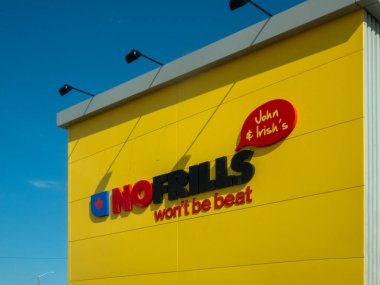 Calgary, Alberta, Kanada. 15 Mayıs 2025. 'John ve İrlandalılar' ile damgalanmış canlı bir No Frills mağazası ve açık mavi gökyüzü altında cesur bir iddia.