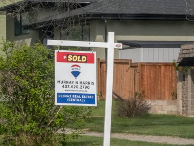Calgary, Alberta, Kanada. 15 Mayıs 2025. REMAX 'tan bir' satıldı 'tabelası, bir emlakçının reklamını yapıyor, bir evin önünde gururla duruyor, başarılı bir emlak alım satımını işaret ediyor..