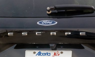 Calgary, Alberta, Kanada. 15 Mayıs 2025. Siyah bir Ford Escape 'in arkasında Ford oval amblemi ve Alberta plakasının üzerinde 