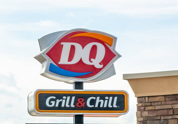 Знаменитая табличка Dairy Queen Grill & Chill стоит перед рестораном, символизируя классическую американскую еду комфорта и замороженные угощения..