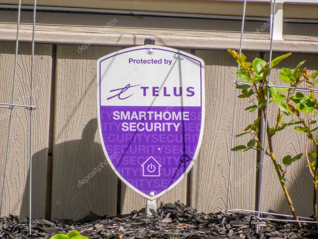 Calgary, Alberta, Canada. May 15, 2025. A Telus Smart Home Security sign, prominently displayed in a yard, signals home protection with its purple and white shield design.