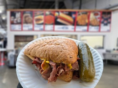 Calgary, Alberta, Kanada. 16 Mayıs 2025. Costco 'dan hardallı ve dereotlu turşulu sıcak Montreal füme etli sandviç klasik bir meze deneyimi sunuyor. Rahatlatıcı yemek..