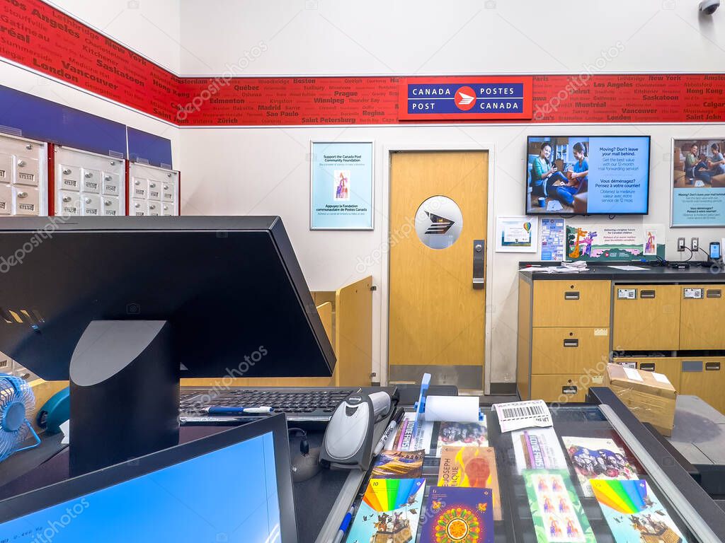 Calgary, Alberta, Canada. May 16, 2025. Inside a Canada Post office, the service counter is ready to assist customers with their mailing needs, surrounded by postal information and branding.