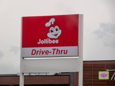 Edmonton, Alberta, Kanada. 21 Mayıs 2025. Canlı bir Jollibee işareti, ikonik maskotu, parlak, bulutlu gökyüzüne karşı popüler fast-food zincirini cesurca ilan eder..