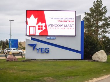 Edmonton, Alberta, Kanada. 24 Mayıs 2025. Bir YEG Edmonton Havaalanı tabelasının bitişiğinde çarpıcı bir dijital reklam panosu var..