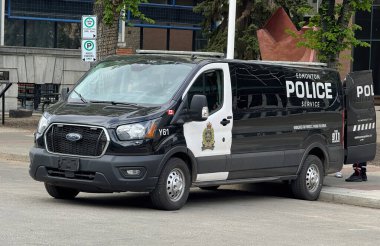 Edmonton, Alberta, Kanada. 21 Mayıs 2025. Bir Edmonton Polis Servisi Ford Transit minibüsü, açıkça belirtilmiş ve teçhizatlı, bir şehir caddesinde duruyor..