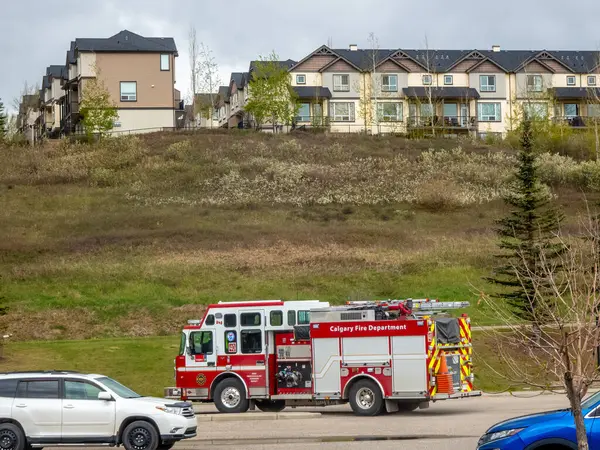 Calgary, Alberta, Kanada. 27 Mayıs 2025. Parlak kırmızı bir Calgary İtfaiyesi kamyonu banliyö caddesinde park halinde. Toplumun güvenliğini ve modern acil servisleri temsil ediyor..